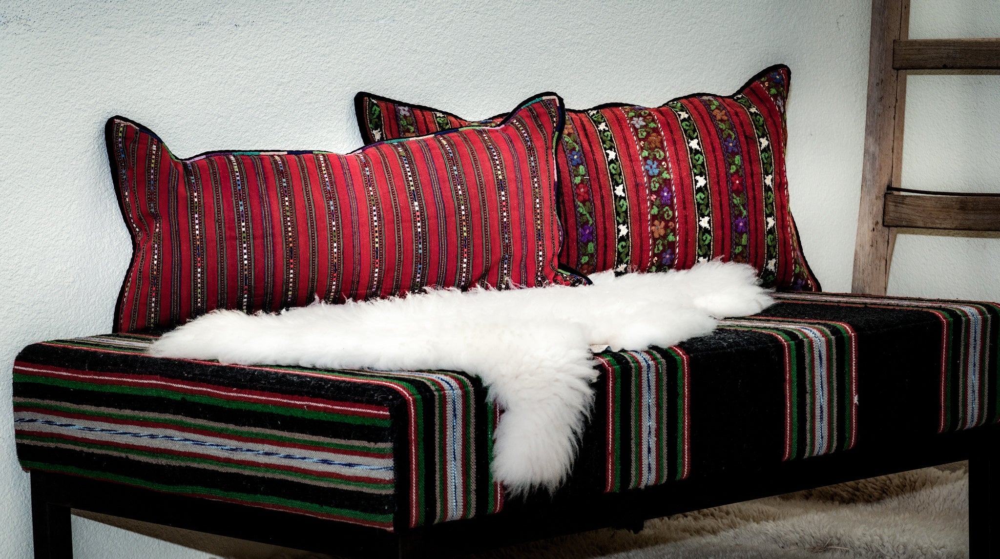 Handwoven Romanian artifact textile pillow on decorative bench.