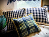 Handwoven antique Bulgarian wool pillows with checkered patterns on a bed.