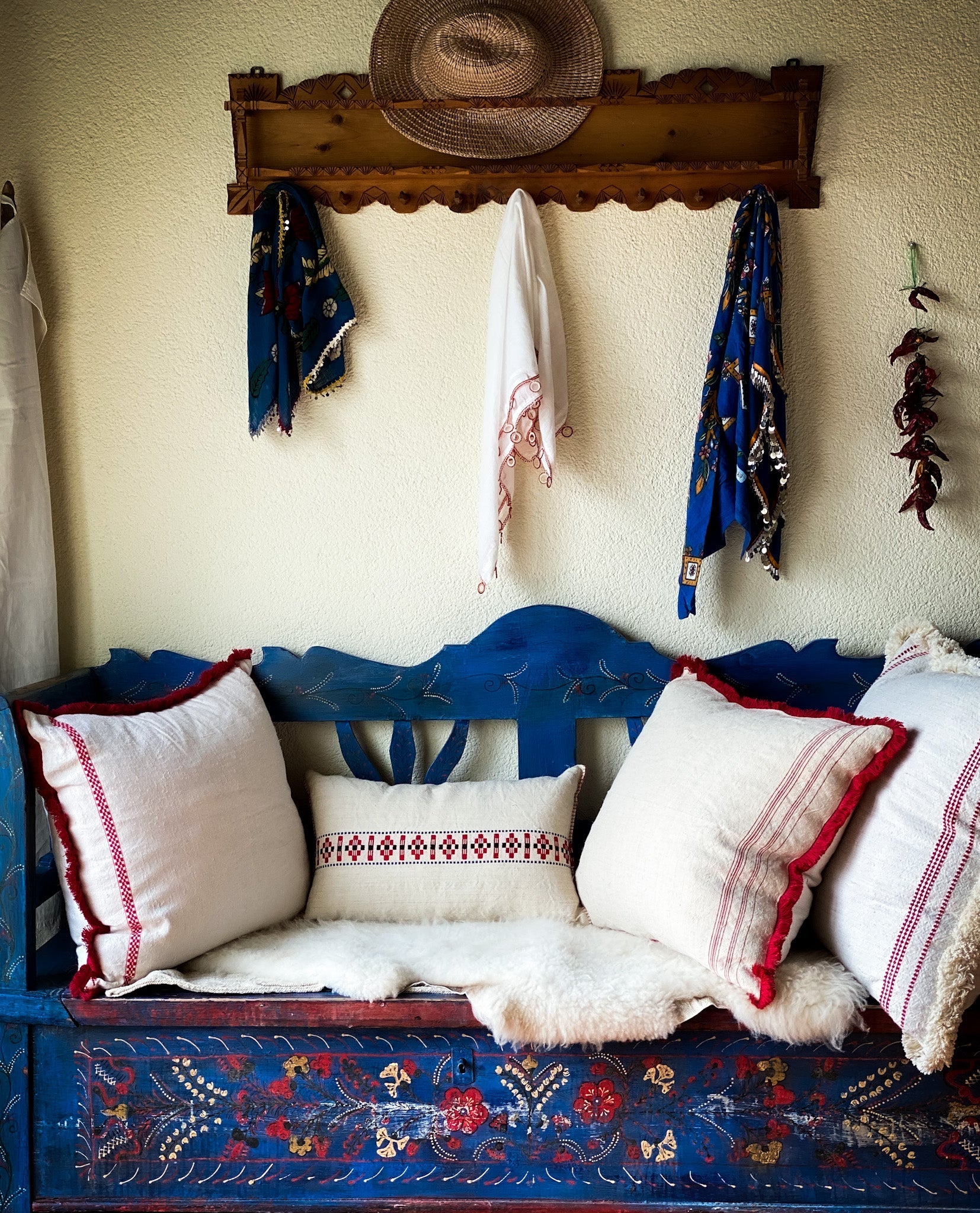 Handwoven antique Hungarian hemp pillow with traditional pattern and cotton fringe on a rustic bench.