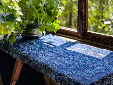 Antique handwoven Hungarian hemp table runner with indigo over dye displayed near a window.