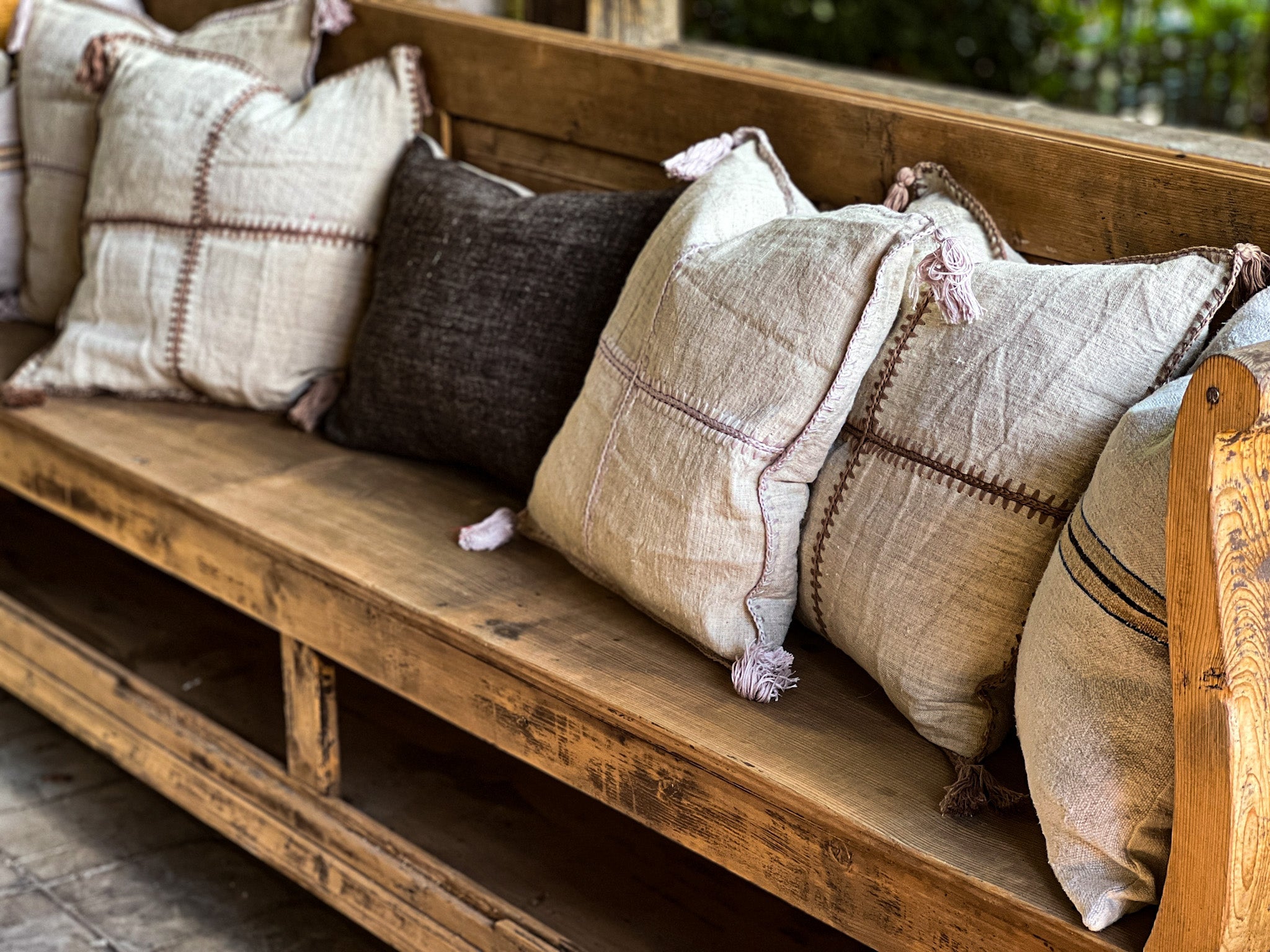 Antique Hungarian handwoven hemp pillows with mauve/taupe stitching on a wooden bench.