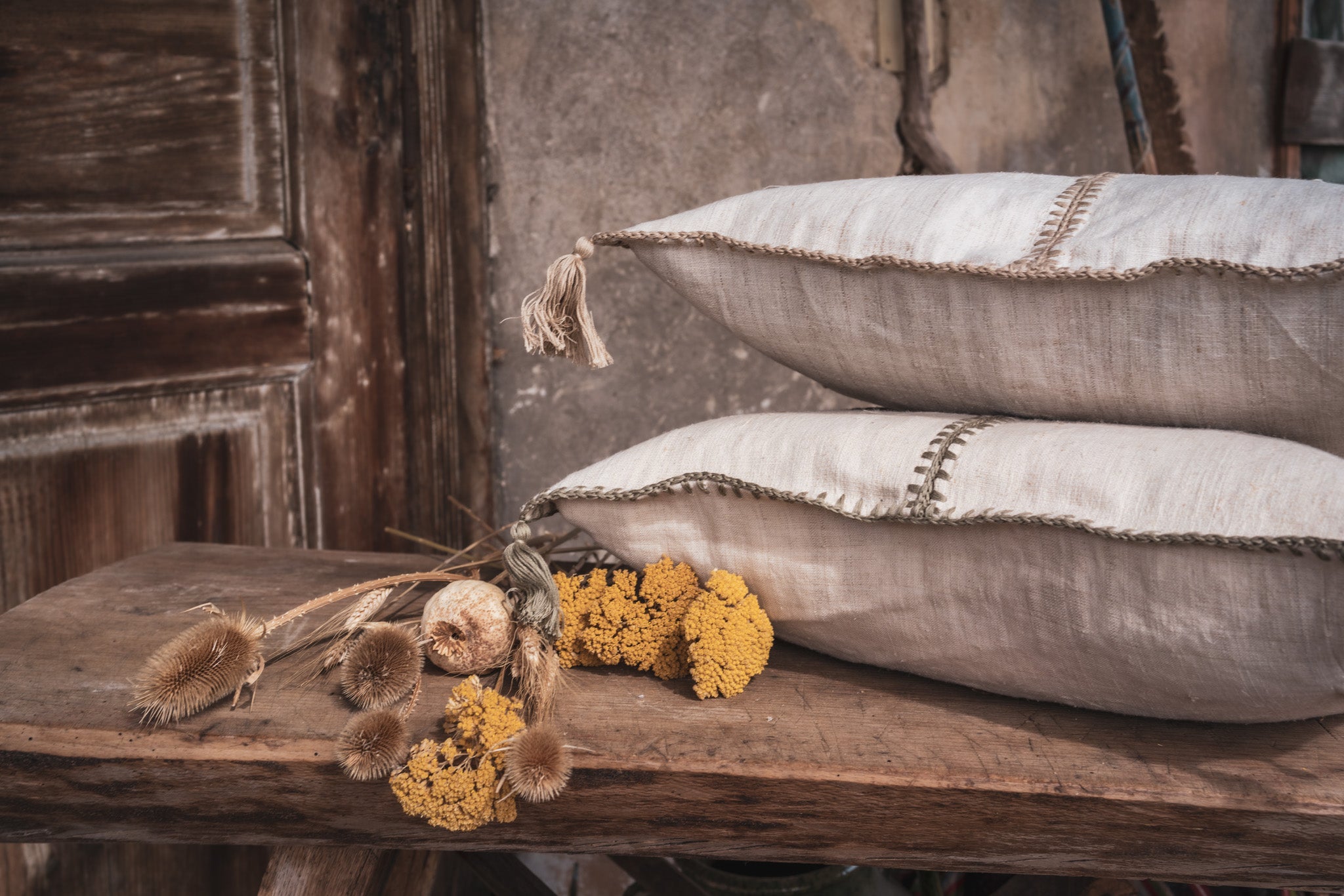 Antique Hungarian handwoven hemp pillows with custom recycled down insert on wooden bench, rustic decor.