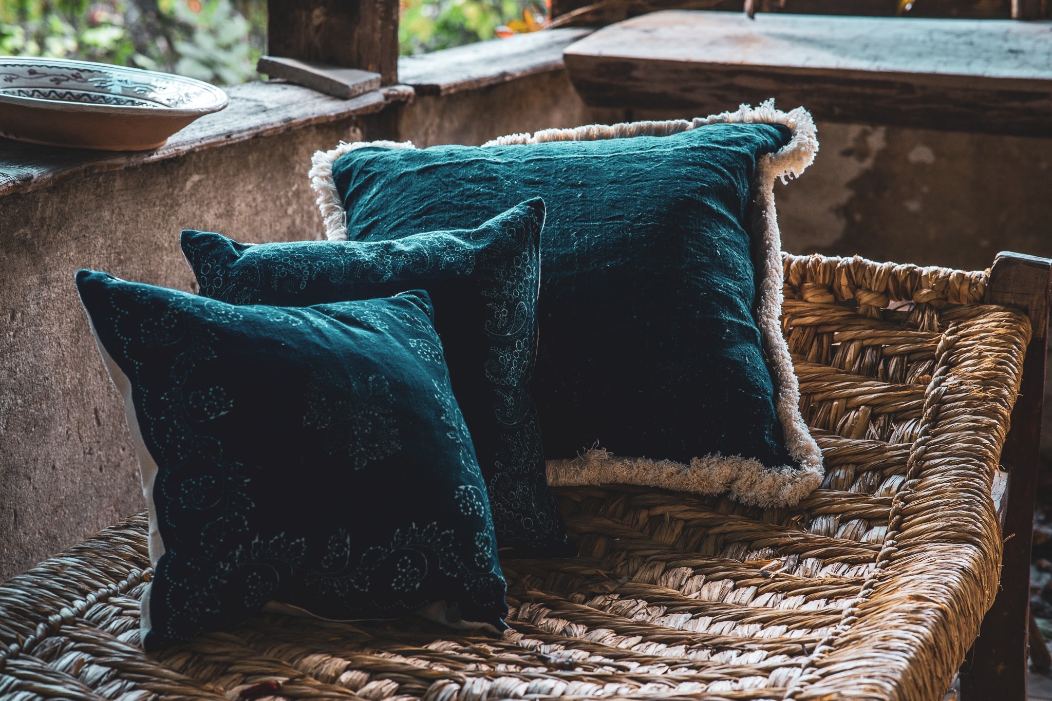 Handwoven antique Hungarian hemp pillows with wax resist dyed indigo, featuring metal zipper, placed on wicker.