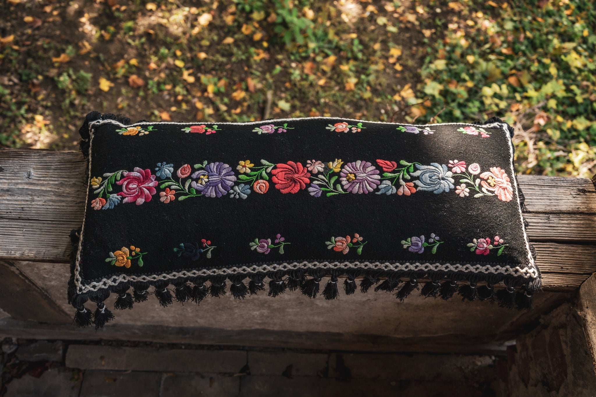 Embroidered handwoven antique Hungarian hemp pillow with floral design and fringe detailing.