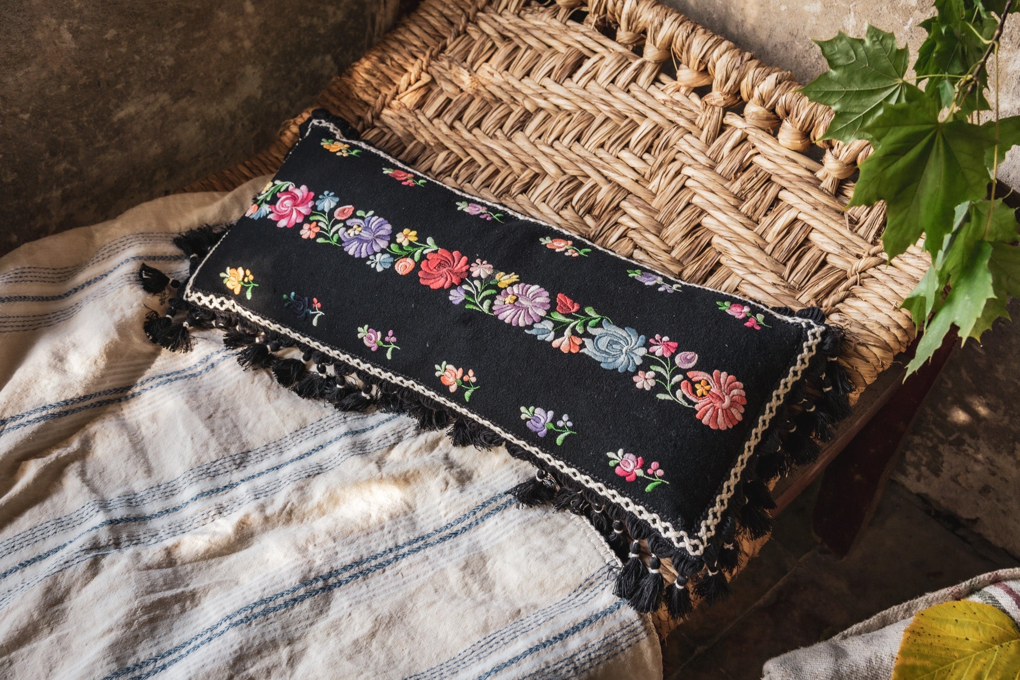 Embroidered handwoven antique Hungarian hemp pillow with floral design and cotton fringe.