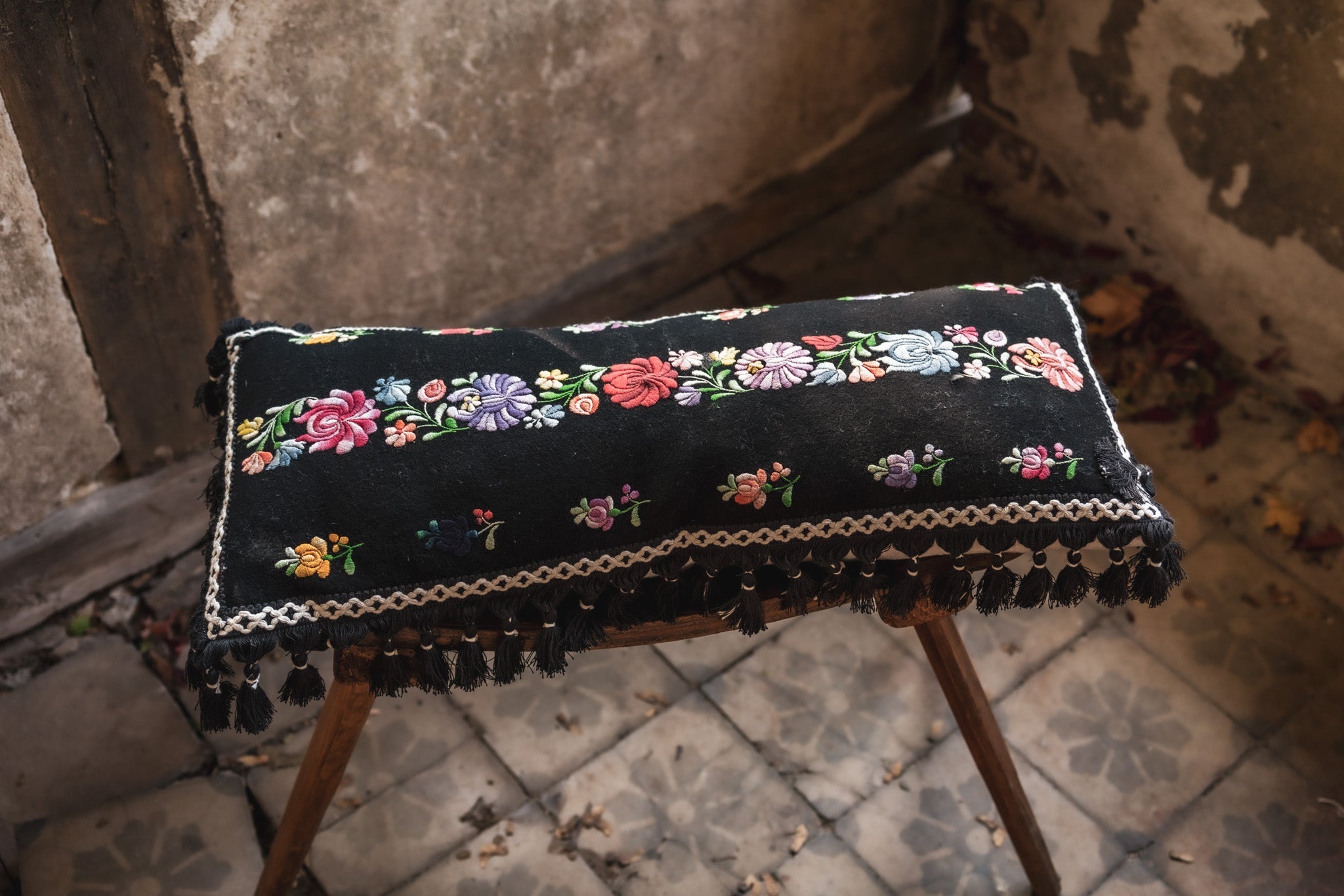 Embroidered handwoven Hungarian hemp pillow with floral design and cotton fringe.