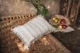 Antique handwoven decorative pillow with cotton fringe on woven bench.