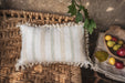 Antique handwoven decorative pillow with cotton fringe on rustic chair.