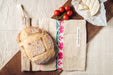 Handwoven antique hemp bread bag with hand embroidery, featuring rustic loaf and cherry tomatoes.