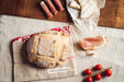 Handwoven antique hemp bread bag with embroidery, holding rustic bread and surrounded by cured meats and cheese.