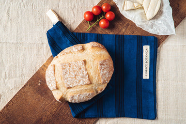 Handwoven antique and vintage hemp bread bag in indigo dye with bread and tomatoes.