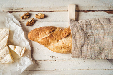 Handwoven antique hemp baguette bag with bread on a rustic surface.