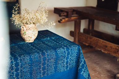 Antique handwoven Hungarian hemp table cloth with indigo dye and decorative border, displayed on table with vase.