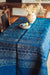 Antique handwoven Hungarian hemp table cloth with wax resist indigo dye and border, displayed on a table with decorative items.