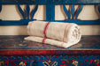 Antique handwoven hemp bedroll on ornate wooden furniture.