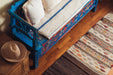 Antique handwoven hemp bedroll on a vintage blue wooden bench.