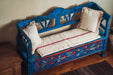 Antique handwoven hemp bedroll on vibrant blue bench with decorative cushions.