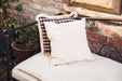 Handwoven antique Bulgarian cotton pillow with goose down, displayed on a rustic bench.