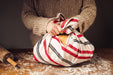 Antique handwoven Bulgarian cotton bag tying closed on a rustic table.