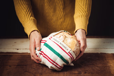 Antique handwoven Bulgarian cotton bag, eco-conscious design, holding bread.