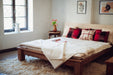 Handwoven artifact textile pillow from Bulgaria on a bed in a cozy room.