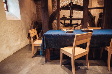 Antique handwoven Hungarian hemp table cloth with indigo dye and yellow pattern on wooden dining table.