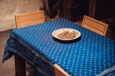 Antique handwoven Hungarian hemp table cloth with indigo wax resist design on table with ceramic plate.