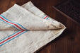 Handwoven antique Hungarian hemp towel with red and blue stripes on a wooden surface.